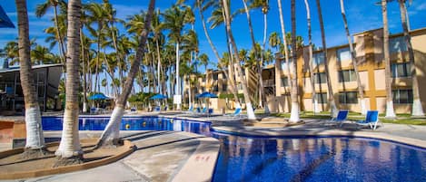 Una piscina al aire libre, sombrillas, sillones reclinables de piscina