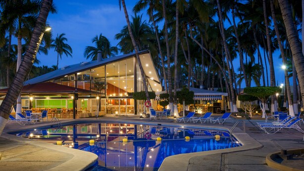 Ein modernes Hotel mit Poolbereich, Palmen und Bar/Lounge.