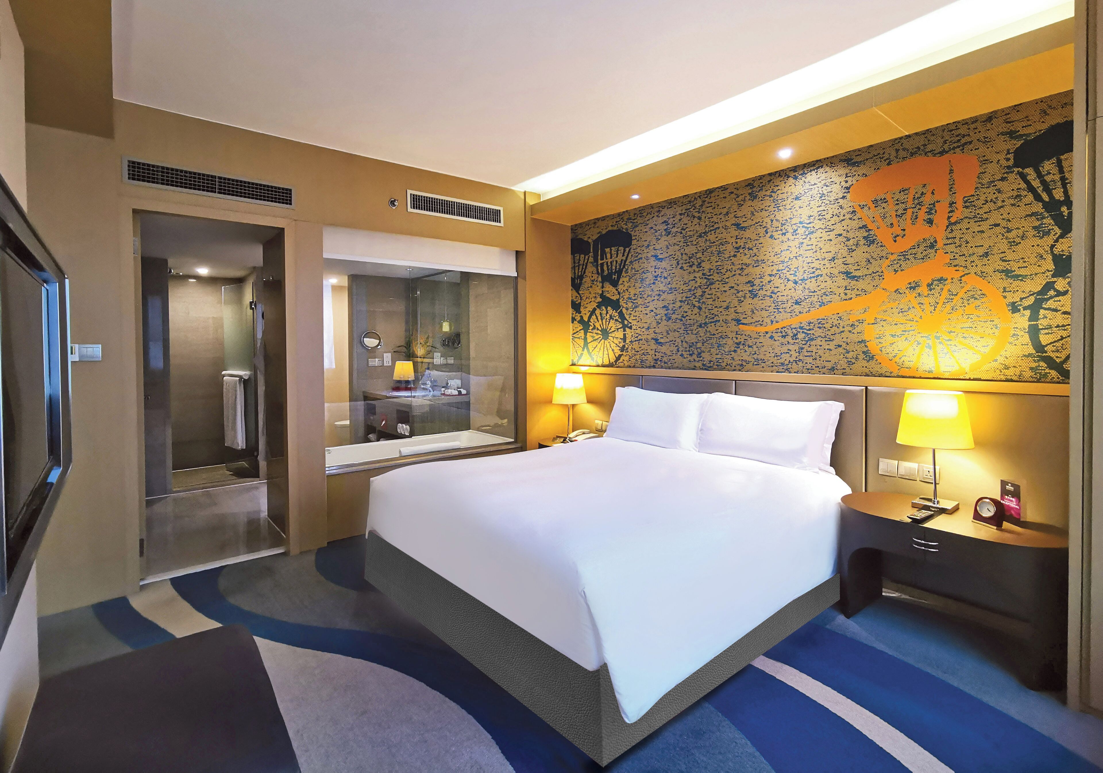 Una habitación de hotel con una cama grande, mesitas de noche con lámparas, un espejo y un mural en la pared.