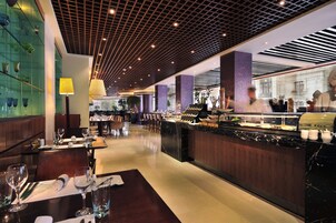 A modern restaurant with a long counter, glass display cases, and a patterned ceiling.