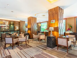 A hotel lobby with a bar area, seating arrangements, and a decorative wall.