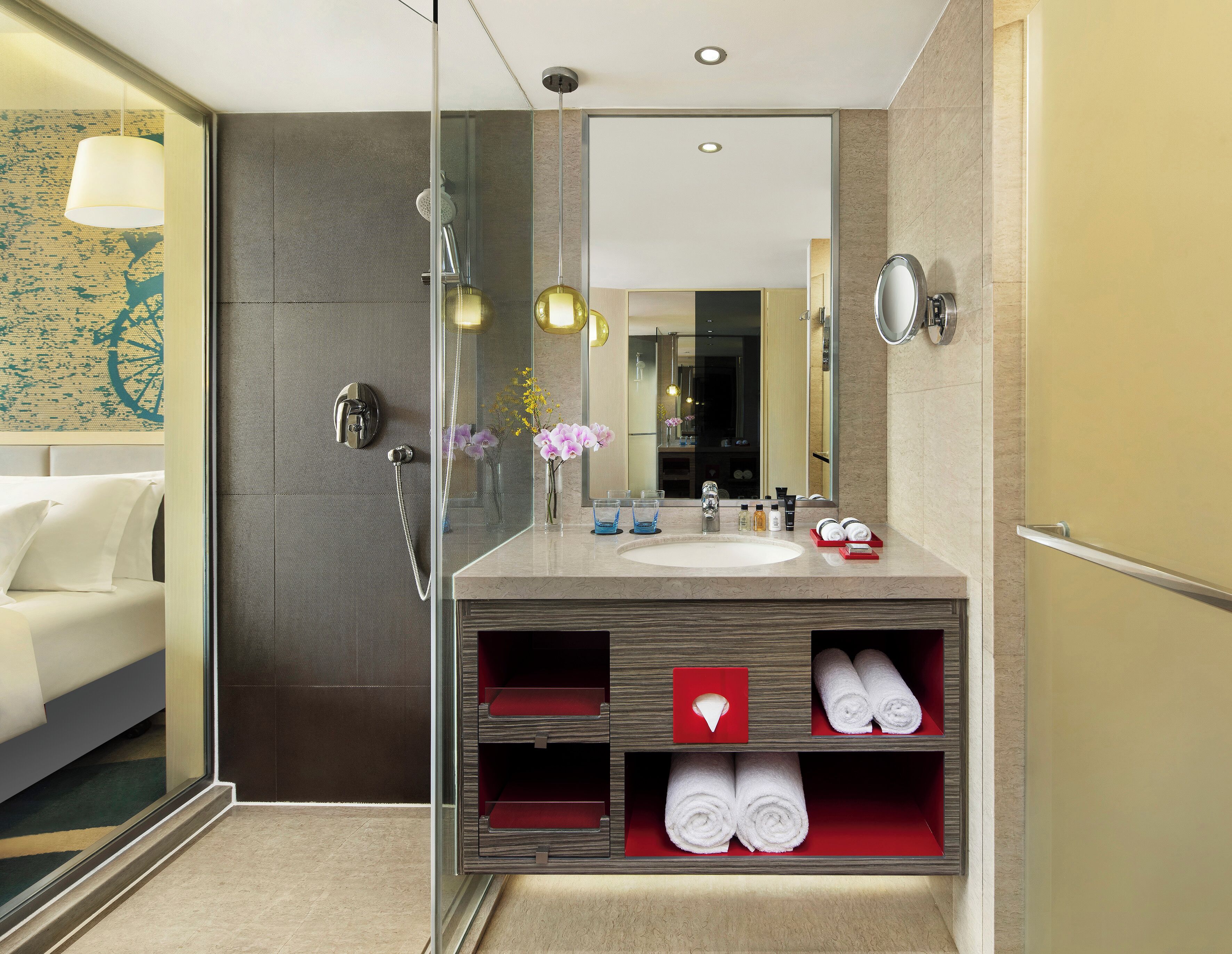 A modern bathroom with a glass shower enclosure, a large mirror, a vanity with a sink, and a built-in shelf with towels.