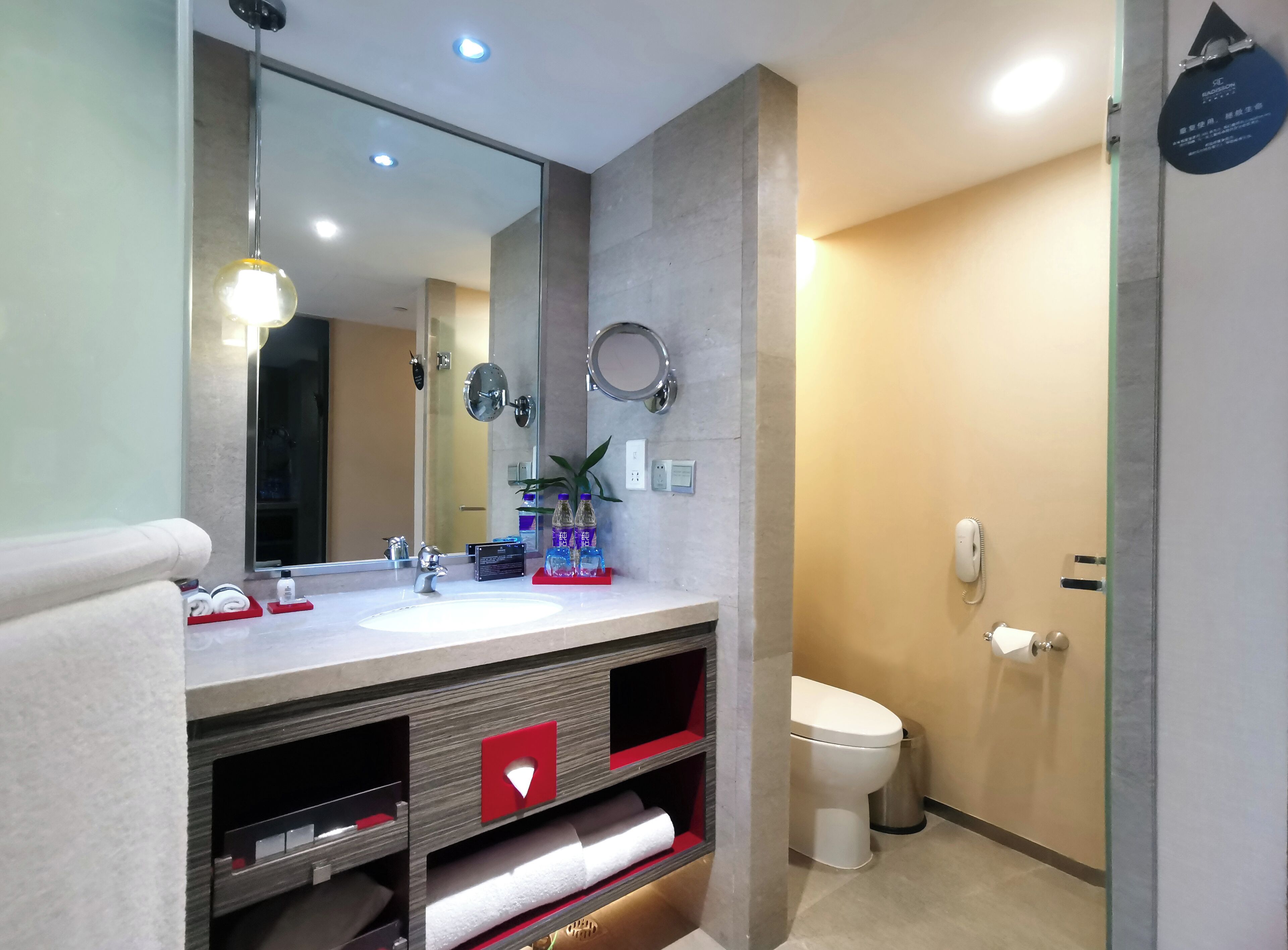 A modern bathroom with a large mirror, a sink, a toilet, and a shower area.