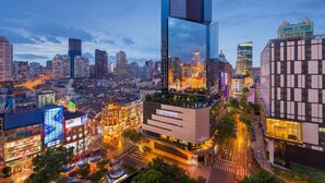 Un paisaje urbano moderno con un rascacielos destacado que tiene un letrero luminoso grande.