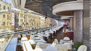 A restaurant with outdoor seating, a view of the city, and a modern interior design.