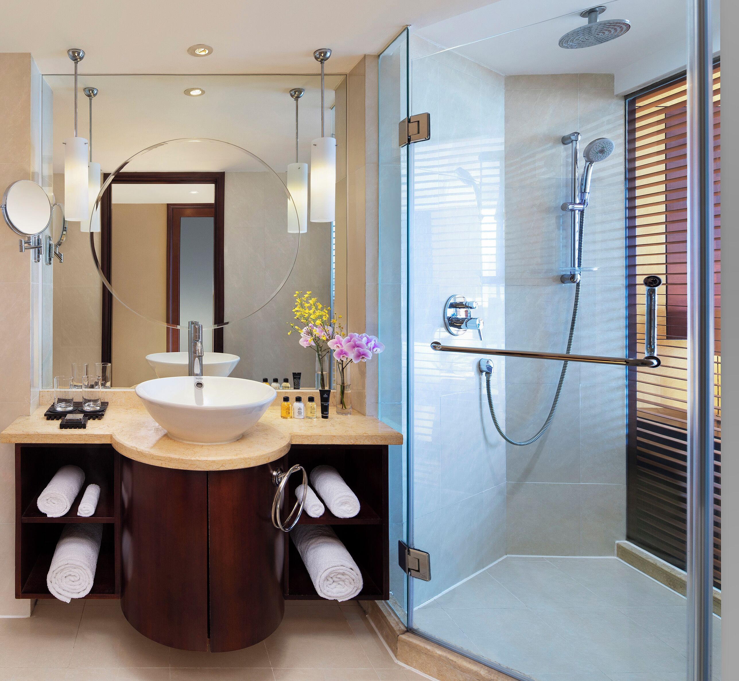 A modern bathroom with a large sink, mirror, and glass shower enclosure.