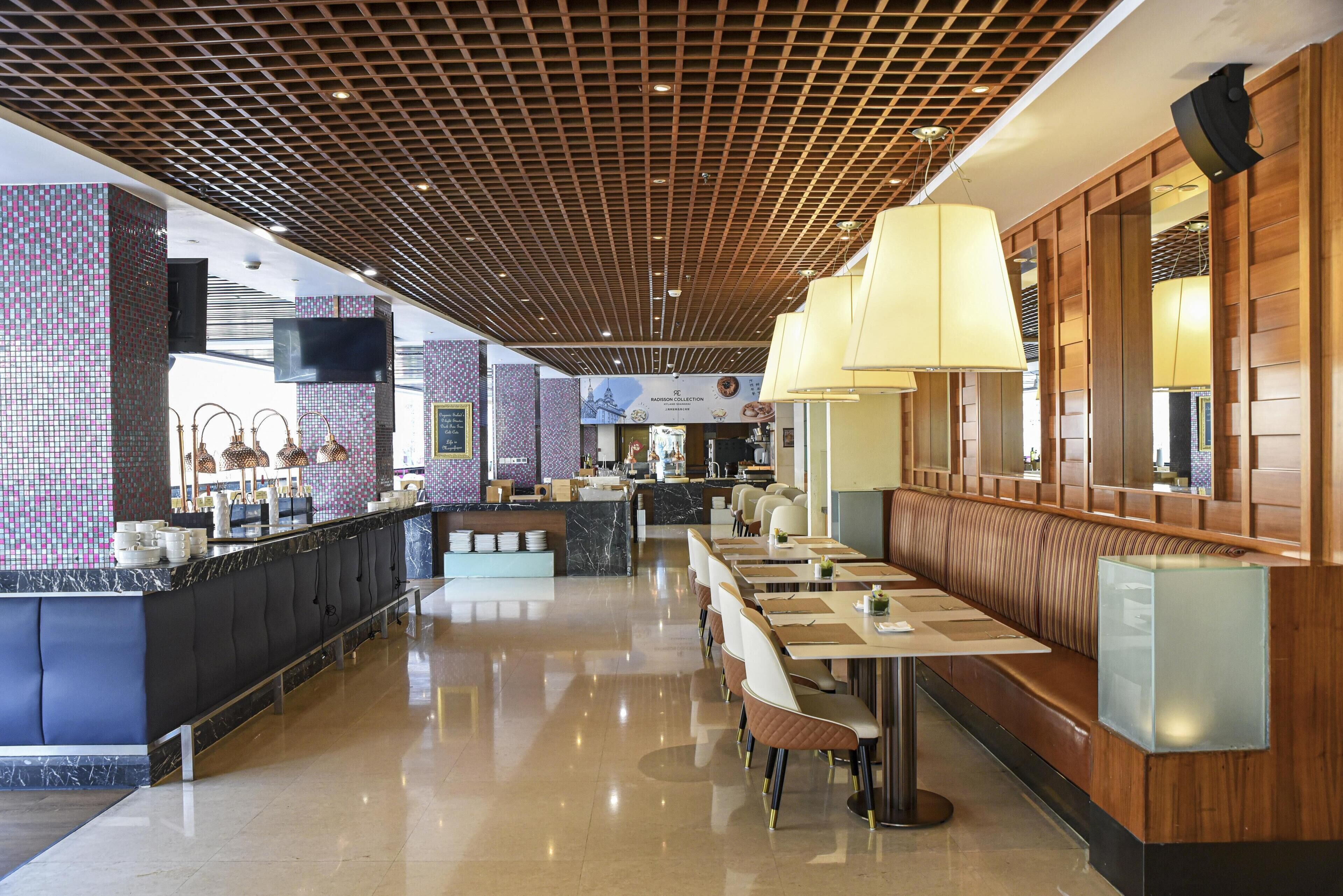 Un restaurante moderno con una barra larga, zona de estar y techo de madera.