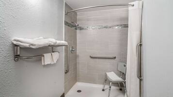 A wheelchair-accessible shower with grab bars, a bench, and a towel rack.