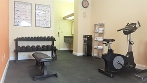 A gym with dumbbells, a bench, and an elliptical machine.