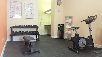 Un gimnasio con mancuernas, un banco y una máquina elíptica.