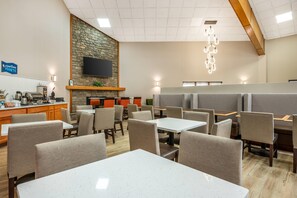 A restaurant with a stone wall, flat-screen TV, and modern lighting. - Clarion Pointe Louisville East (Louisville)