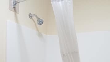 Eine weiße Badewanne mit Duschbrause und Vorhang.