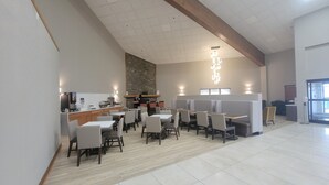 A spacious dining area with high ceilings, a stone accent wall, and modern lighting fixtures.