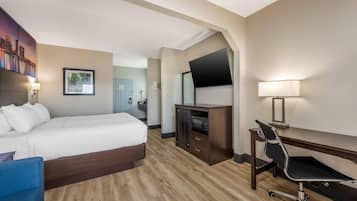 Une chambre d’hôtel équipée d’un lit, d’un bureau, d’une chaise, d’un téléviseur et d’un téléviseur fixé au mur.