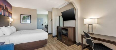 A hotel room with a bed, a desk, a chair, a television, and a wall-mounted TV.
