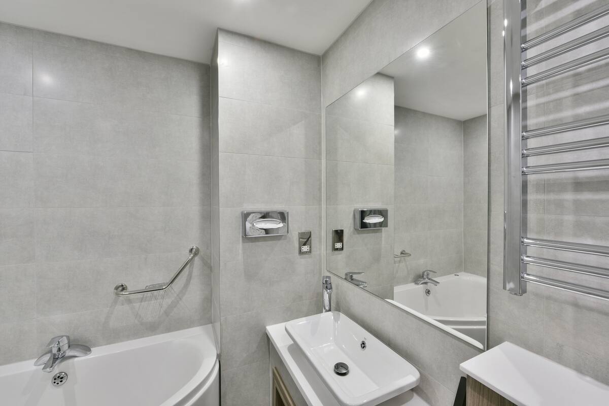 A modern bathroom with a large bathtub, a sink, and a mirror.
