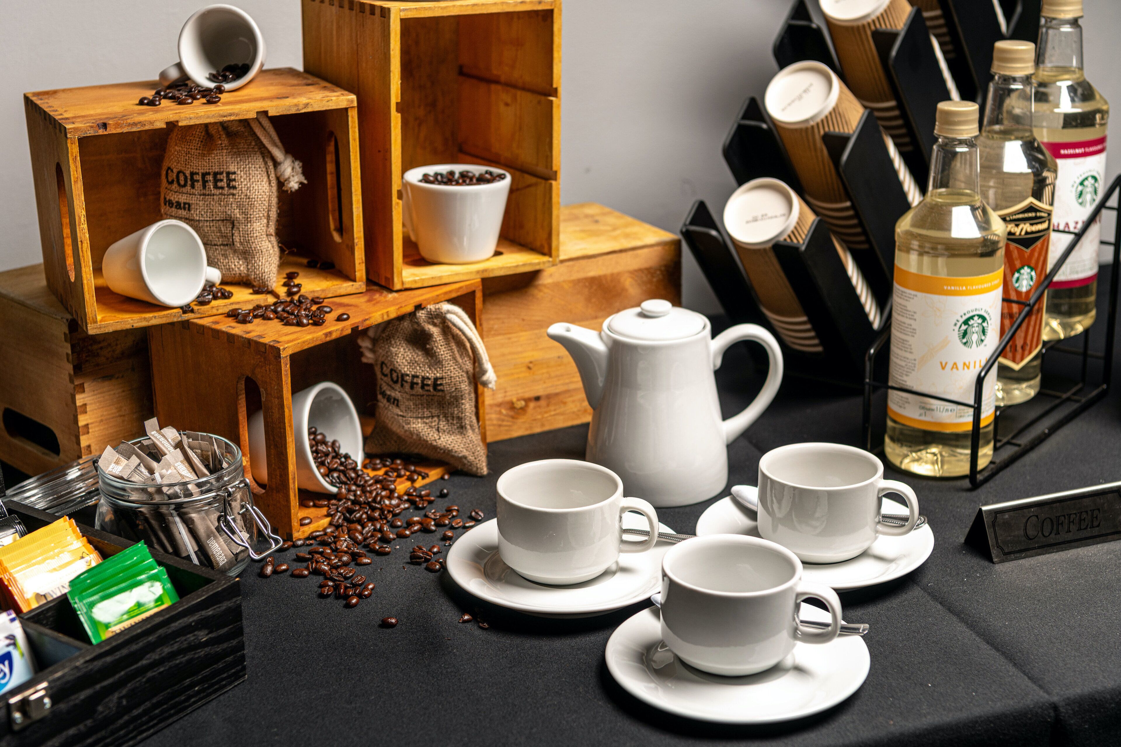 Estación de café con un molinillo, un hervidor y diferentes tazas y platones.