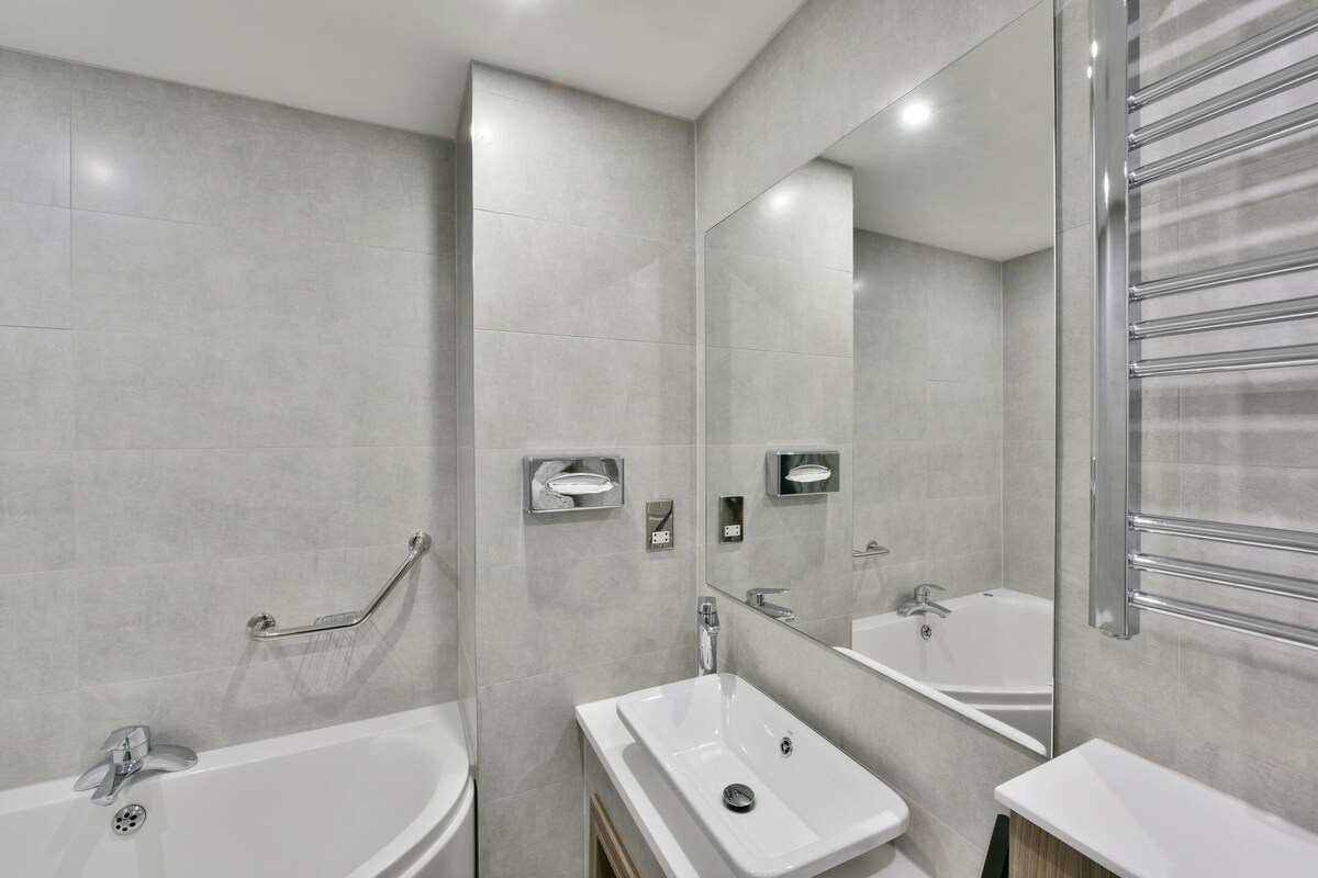 Un baño moderno con bañera, lavamanos, espejo y toallero.