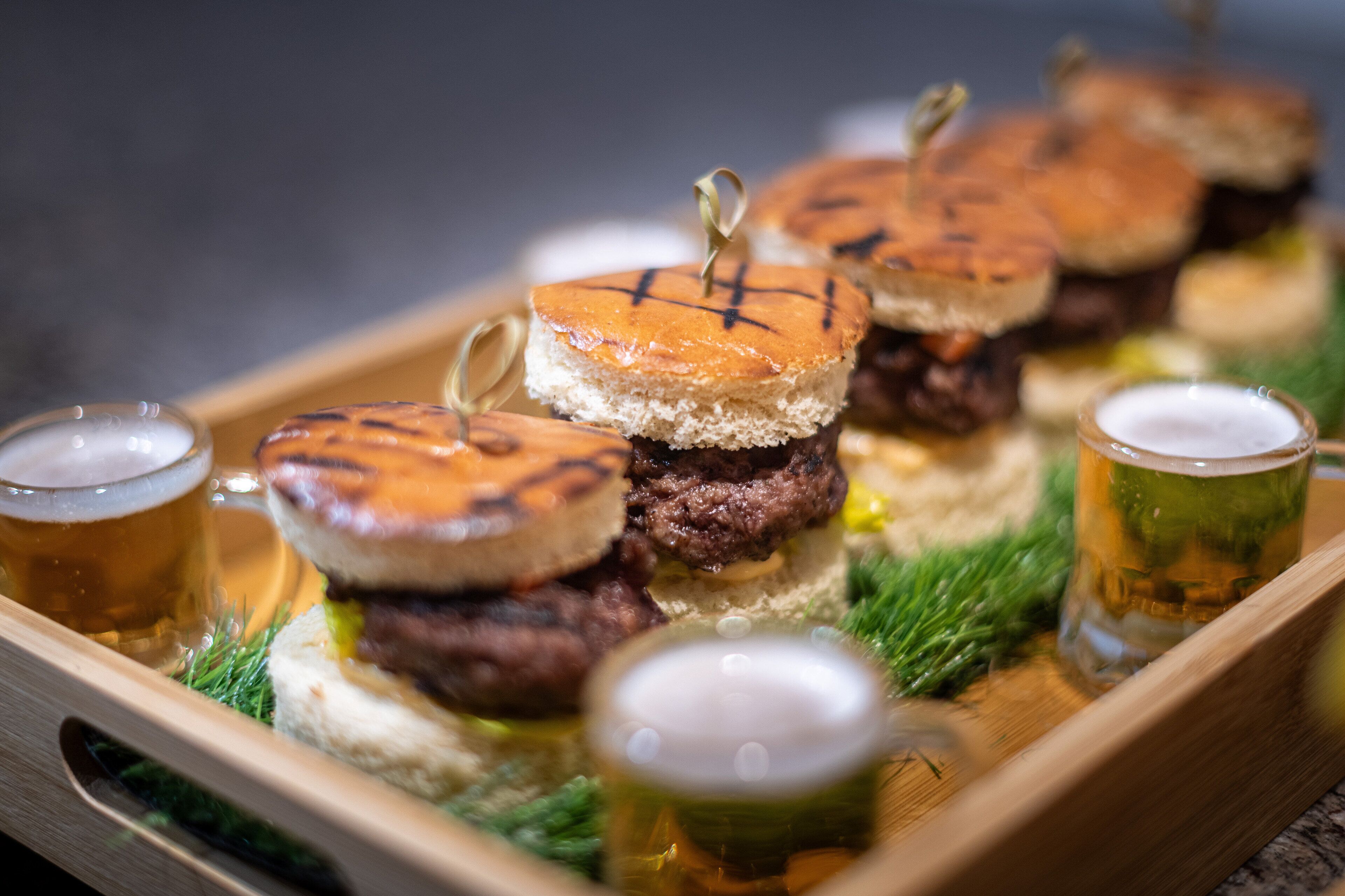 A tray with grilled burgers and beer glasses.