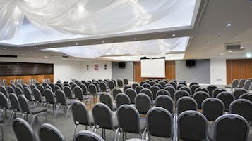 A conference room with rows of chairs, a projector screen, and a large white draped ceiling.