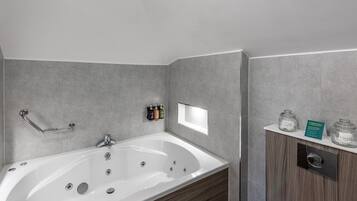 A modern bathroom with a freestanding bathtub, a handrail, and a vanity with a mirror and storage jars.