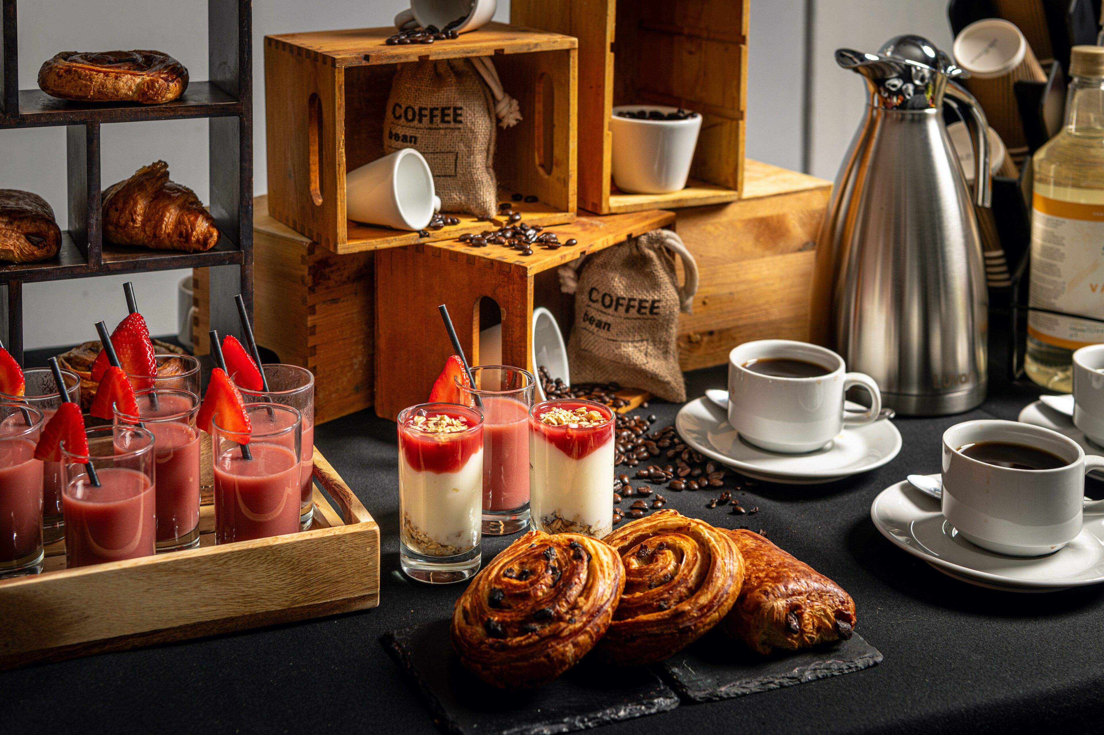 A breakfast setting with pastries, coffee, and smoothies.