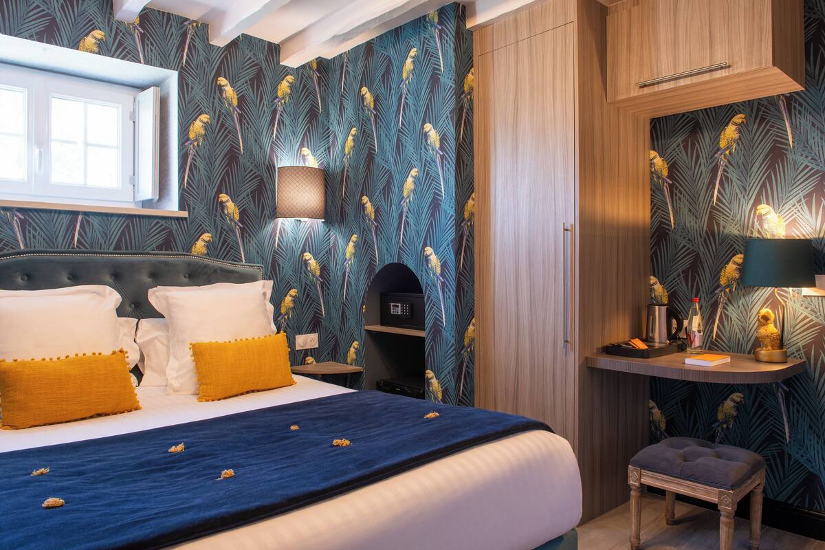 A bedroom with a large bed, a nightstand, a small table, and a mirror.