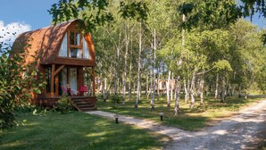 A wooden cabin with a porch, surrounded by trees and a dirt path. - Hôtel Relais des Landes - Demeures et Châteaux (Le Controis en Sologne)