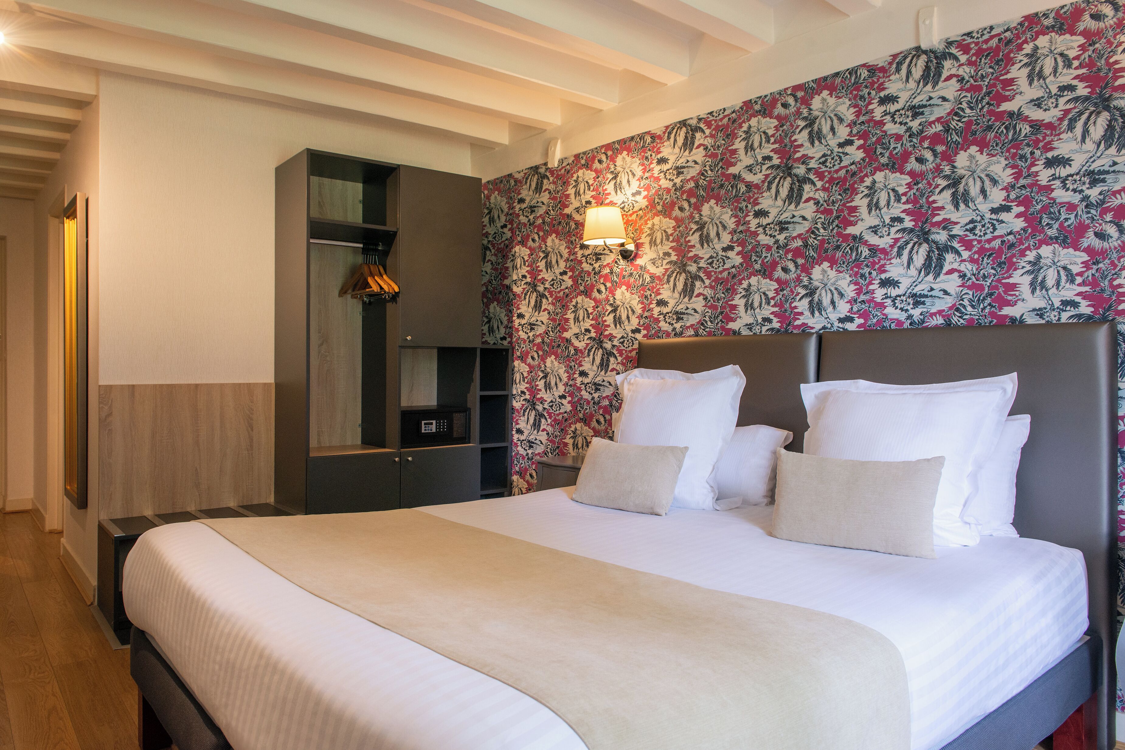 Una habitación de hotel con una cama grande, un armario y un papel tapiz floral.