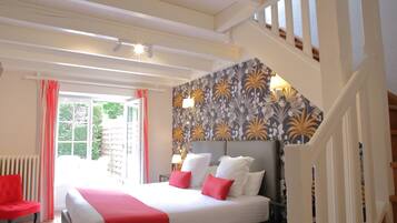 Une chambre d’hôtel avec un grand lit, un fauteuil rouge et un escalier.