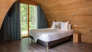 A bedroom with a sloped ceiling, wooden walls, a large bed with pillows, and a window with curtains. - Hôtel Relais des Landes - Demeures et Châteaux (Le Controis en Sologne)
