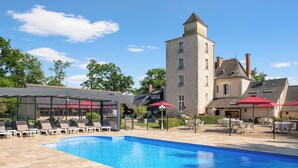 A swimming pool with lounge chairs and umbrellas, a covered seating area, and a large building with a tower. - Hôtel Relais des Landes - Demeures et Châteaux (Le Controis en Sologne)