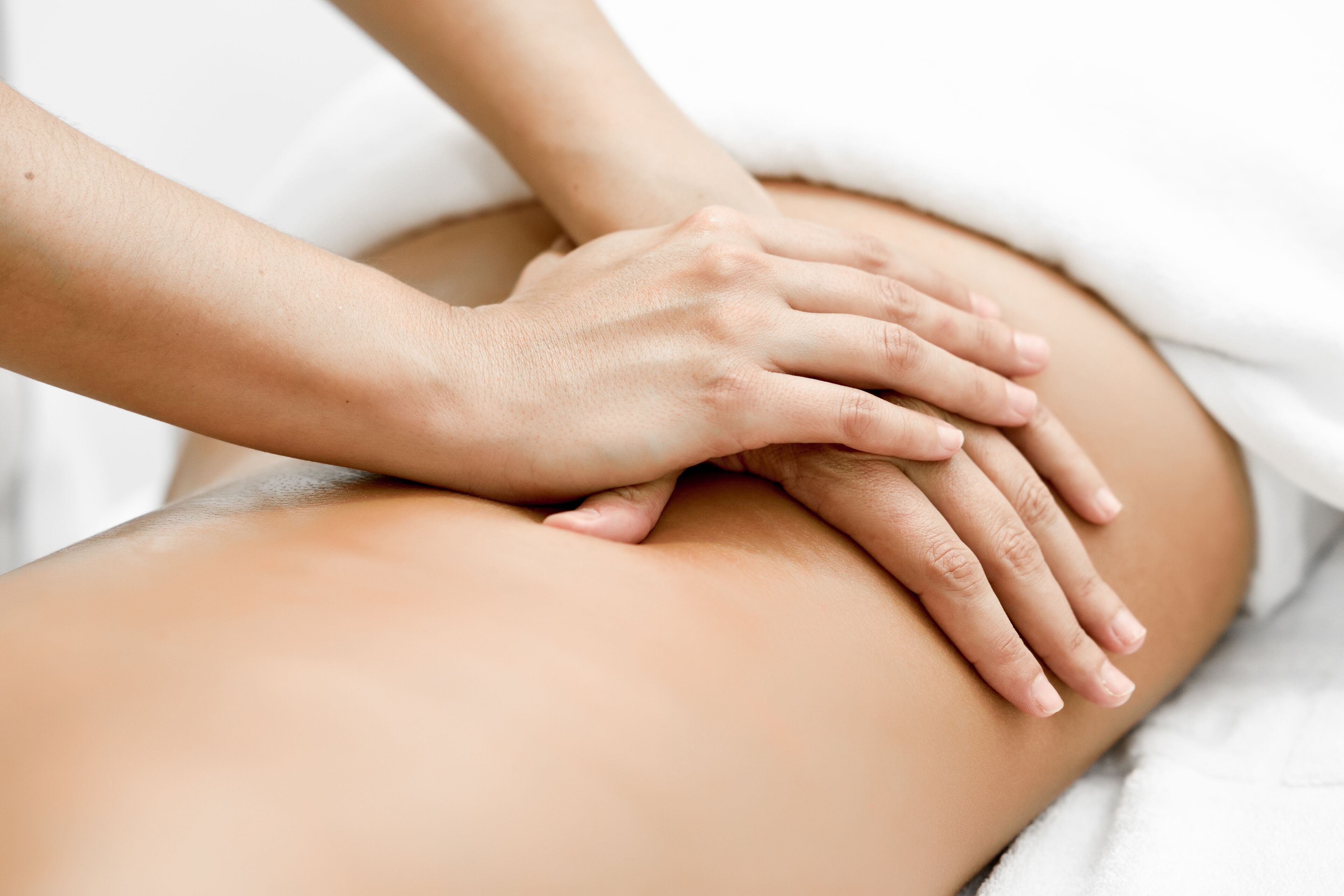 A close-up of hands performing a massage on a person's back.