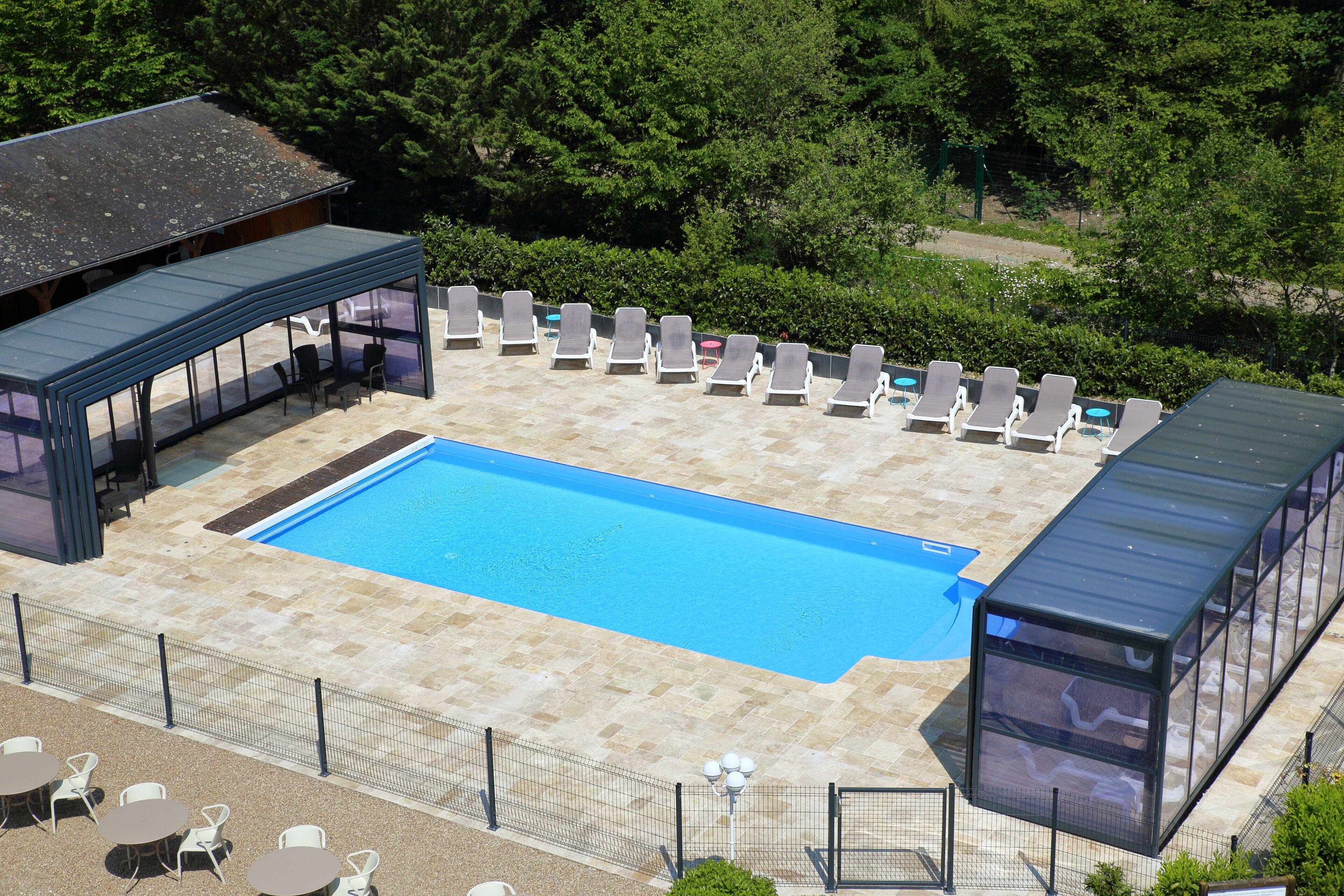 Piscina com espreguiçadeiras e área de estar coberta.