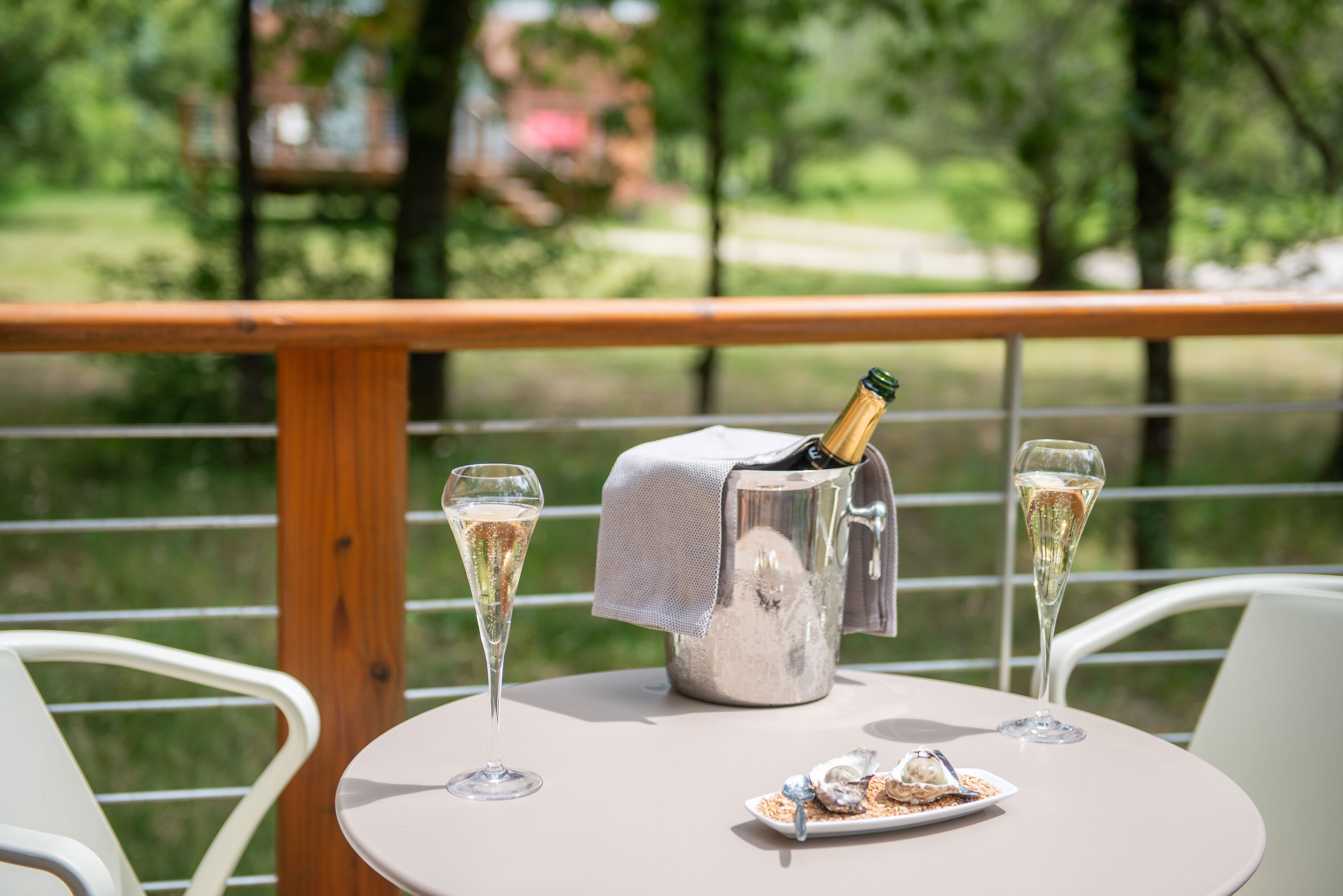 Een tafel met twee champagneglazen, een metalen emmer en een bord dessert.