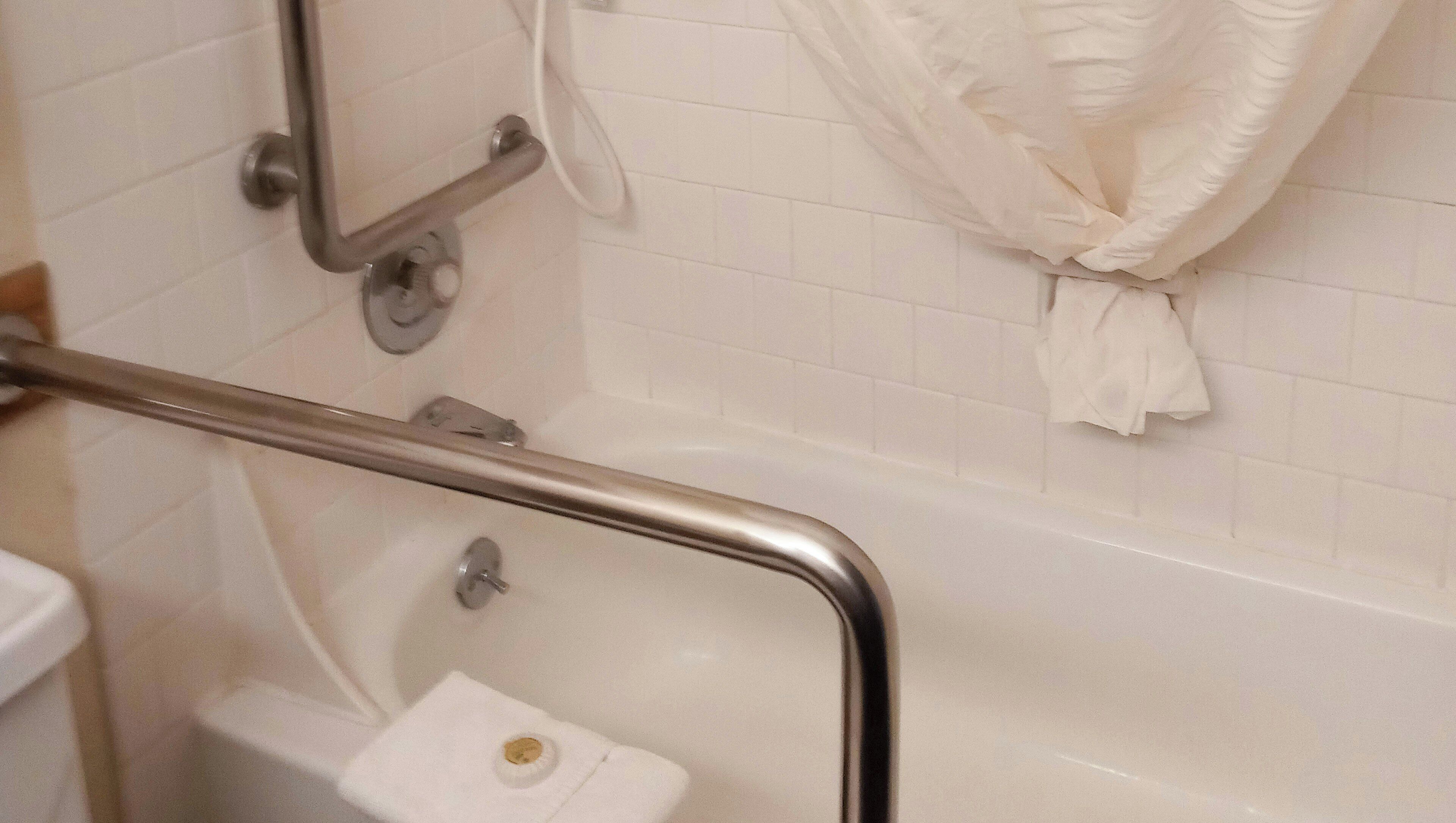 A bathroom with a white bathtub, a toilet, and a shower area.