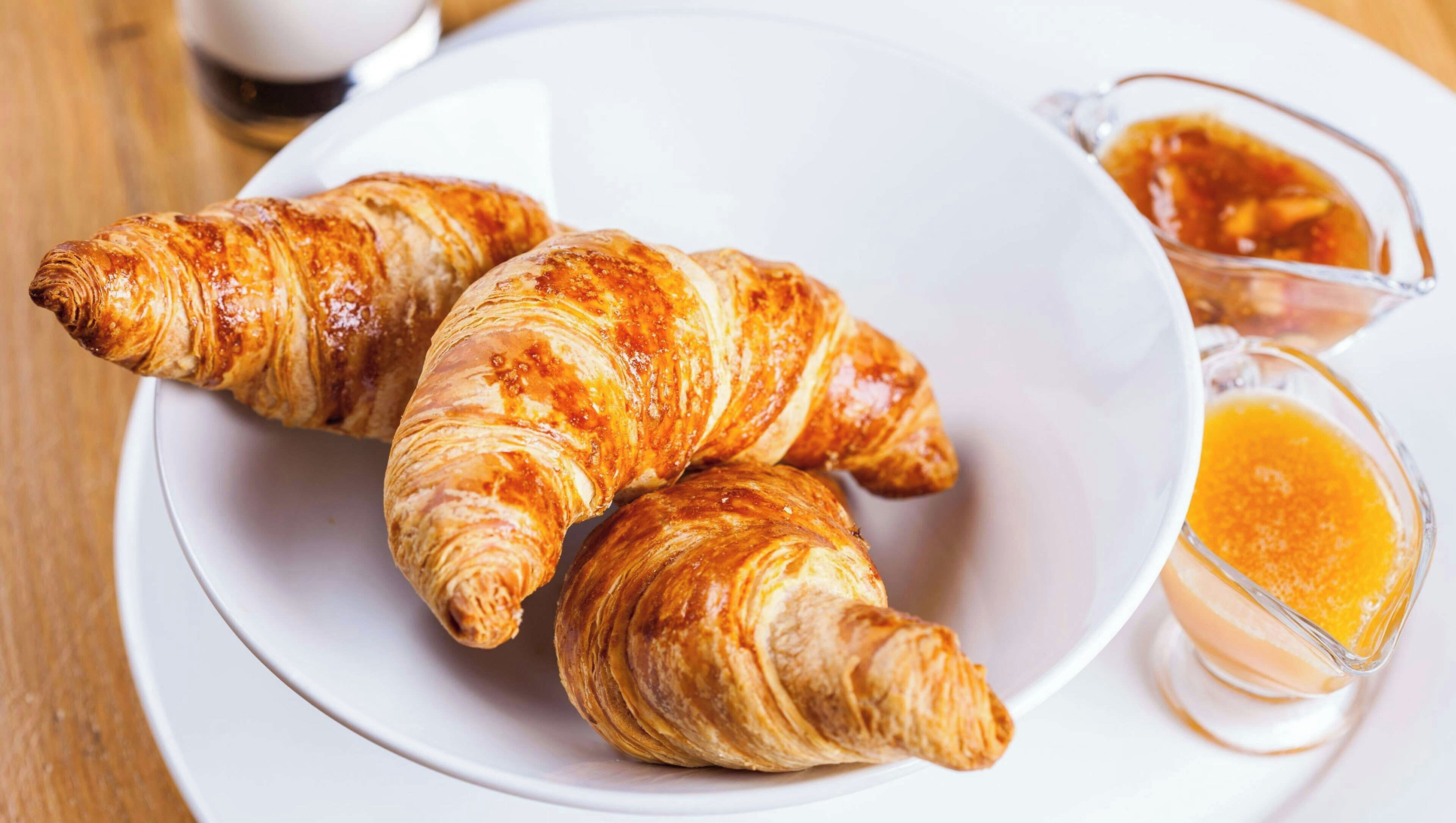 A plate with croissants and a glass of orange juice.