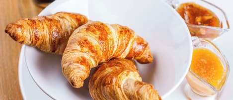 Um prato com croissants e um copo de sumo de laranja.