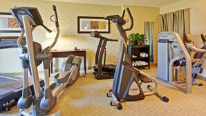 Une salle de sport d’hôtel équipée d’un tapis de course, d’un vélo elliptique et d’appareils de musculation.