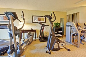 Gimnasio de hotel con cinta de correr, elíptica y máquinas de pesas.