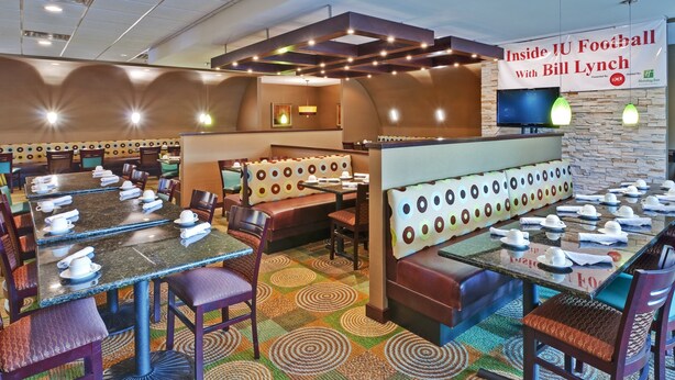 Un restaurant avec des banquettes et des tables, une enseigne et un téléviseur.