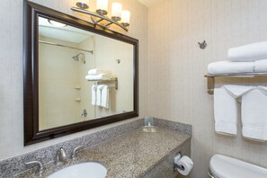 Une salle de bain dotée d’un grand miroir, de deux lavabos, de toilettes et d’un porte-serviettes avec plusieurs serviettes.
