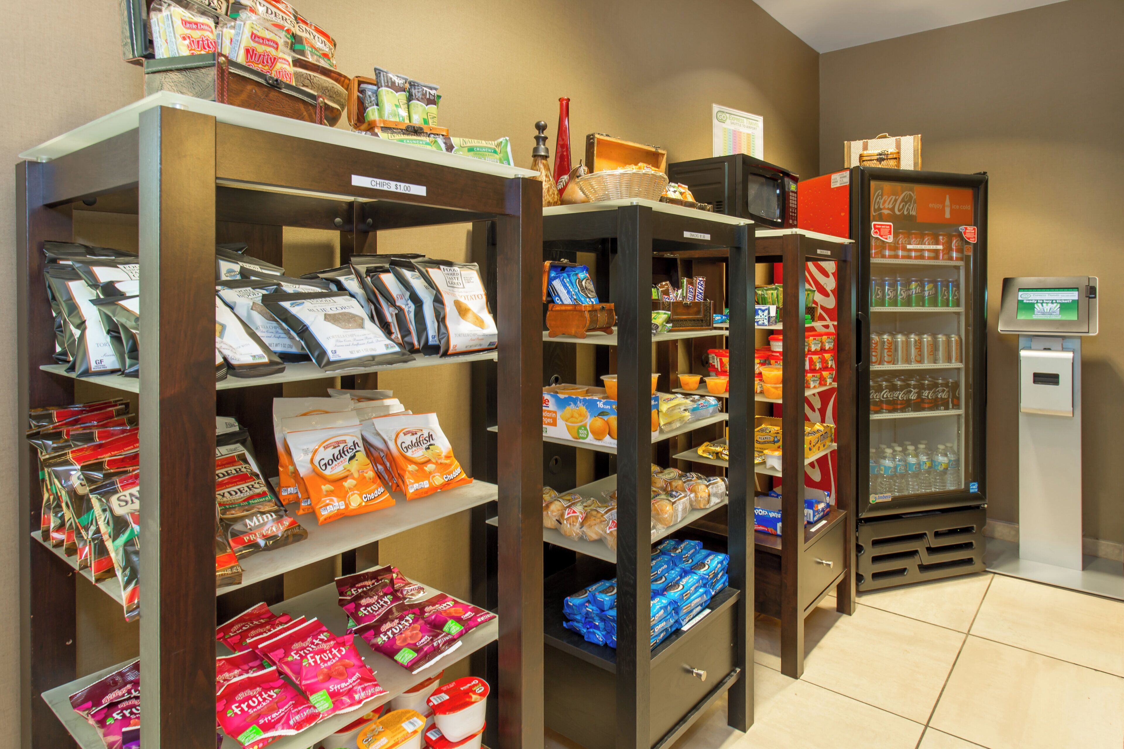 A snack and beverage vending area with various snack options and a Coca-Cola refrigerator.