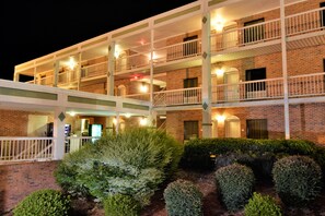 A multi-story hotel with balconies, a brick facade, and a well-lit entrance. - Rodeway Inn Harbison Area (Columbia)