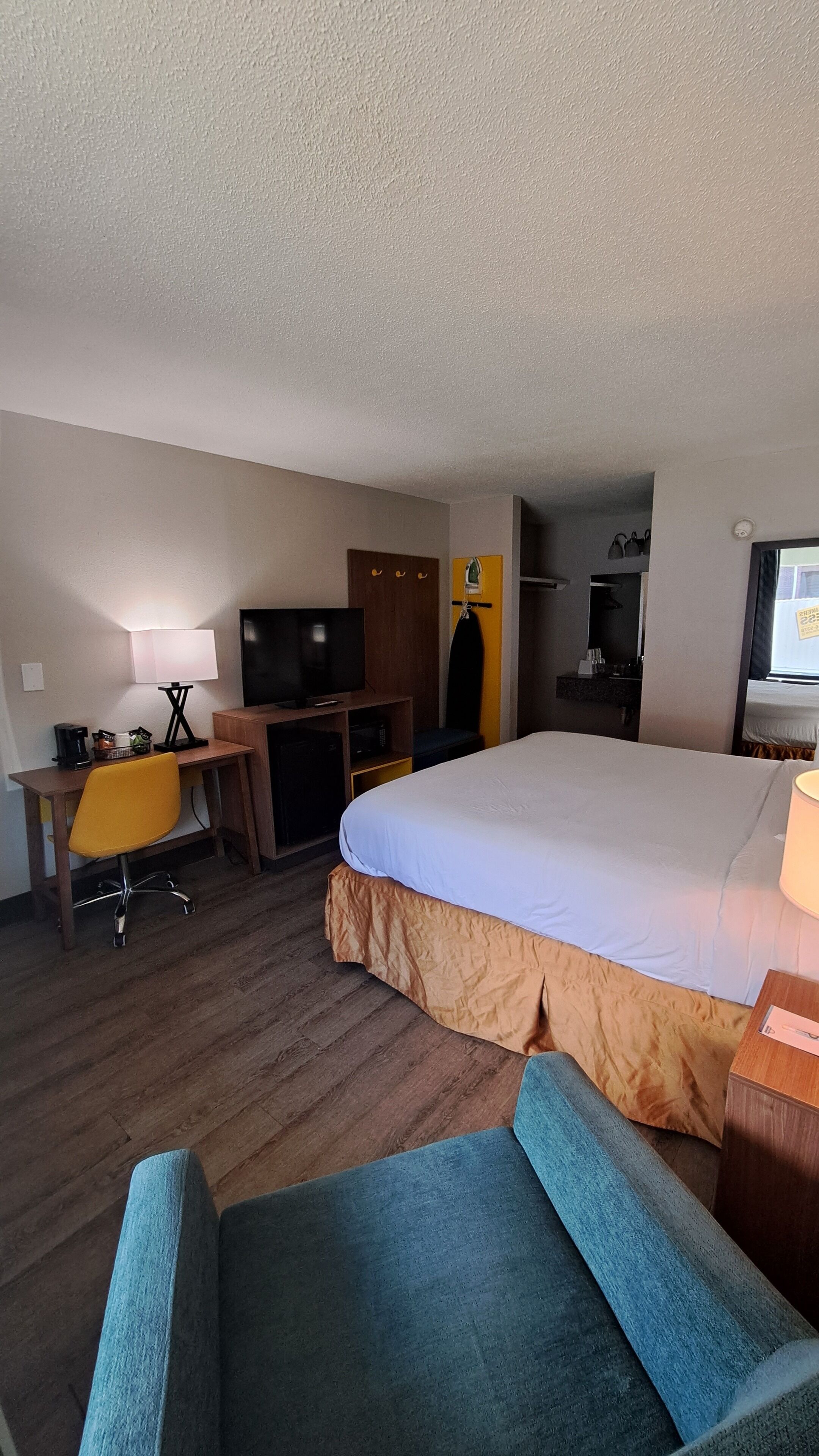 A hotel room with a bed, a desk, a television, a chair, and a wardrobe.