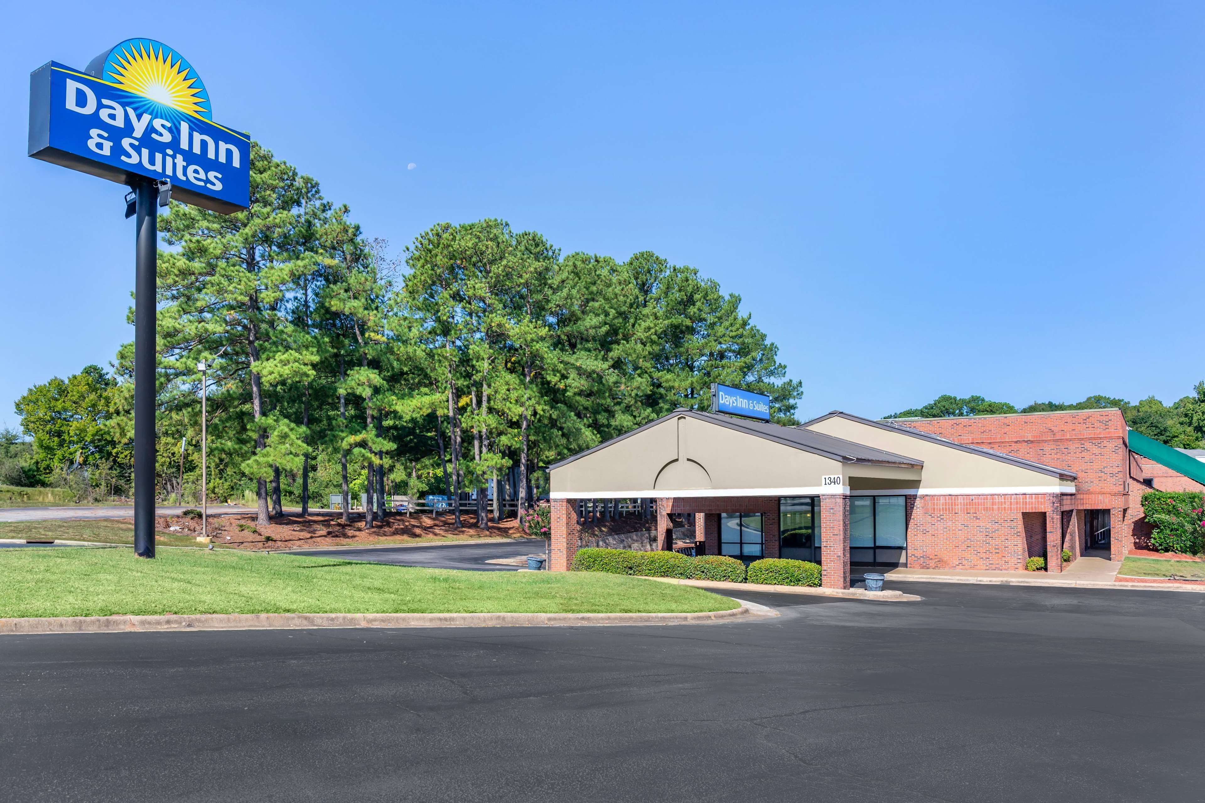 Une enseigne Days Inn & Suites, un bâtiment en briques doté d’une entrée abritée et un parking.