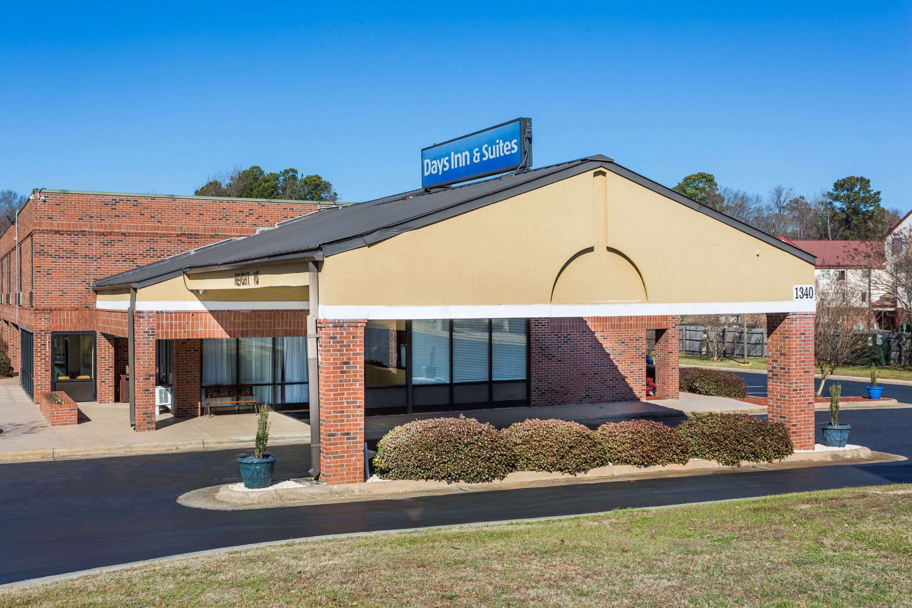 A Days Inn & Suites building with a brick facade, large windows, and a covered parking area.