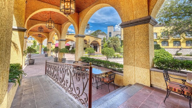 An outdoor covered patio with arches, a table, chairs, and potted plants. - Holiday Inn Queretaro-Centro Historico by IHG (Querétaro)