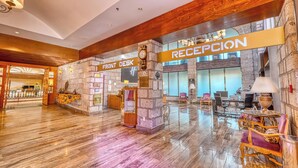 A hotel lobby with a reception area, a front desk, and a stone wall. - Holiday Inn Queretaro-Centro Historico by IHG (Querétaro)