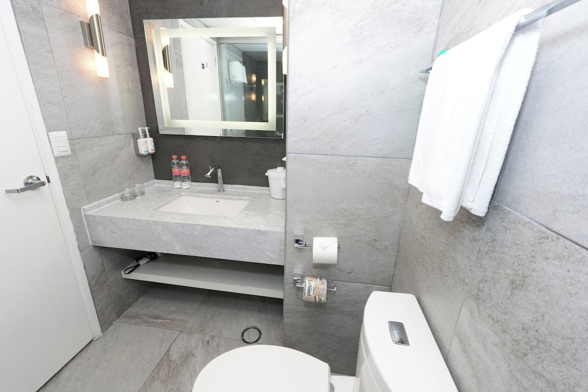 A modern bathroom with a large mirror, a sink, and a toilet.
